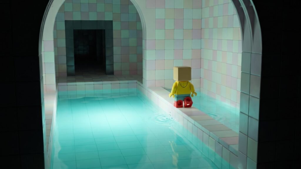 Blocky toy character tiptoeing along a tiled ledge beside glowing turquoise water in an eerie poolroom