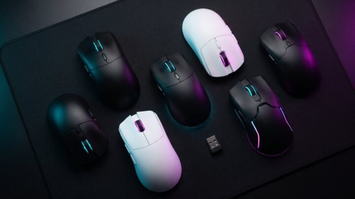 Six white and black gaming mice on a dark desk mat